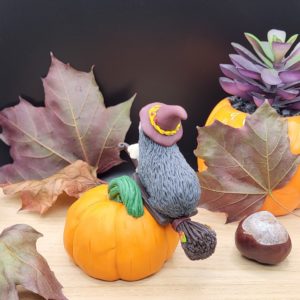 Grey guinea pig flying on a broomstick. The piggy sits on top of a giant pumpkin. The guinea pig is wearing a witch hat. There's a little ghost companion sitting on the front of the broomstick.
